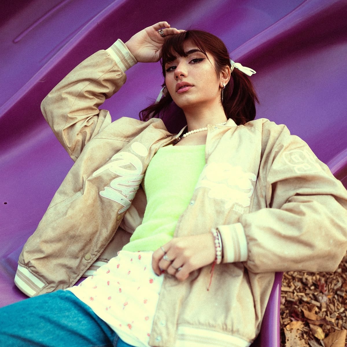Asal Dabbaghchian leaning back on a purple playground slide in a varsity jacket