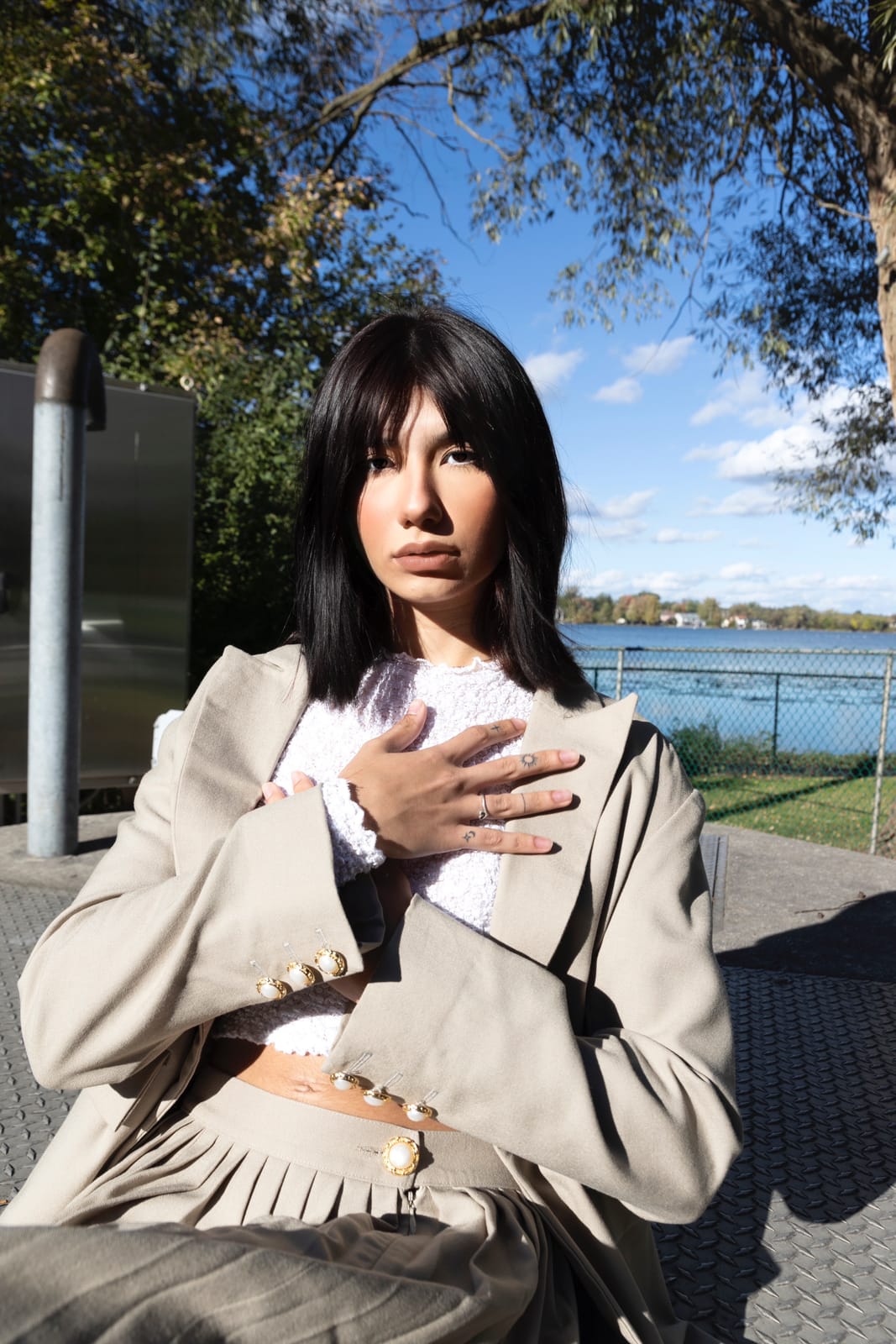 Asal Dabbaghchian comp card portrait, seated by a lake in a beige blazer